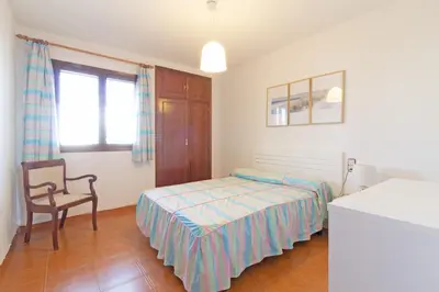 a bedroom with a bed and a chair and a window at Global Vacacional, Adosado con piscina en la playa de Canet in Canet de Berenguer