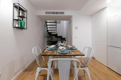 a dining room with a wooden table and white chairs at DormForYou Alameda 12 Apartment in Valencia