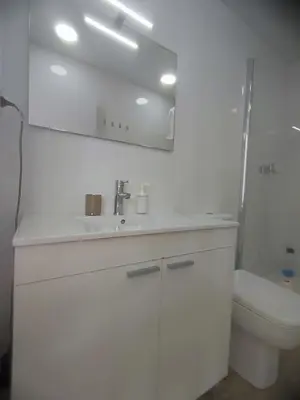 a white bathroom with a sink and a toilet at Bright loft near the sea + BIKES in Valencia