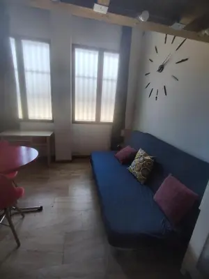 a living room with a blue couch and a clock on the wall at Loft duplex industrial near the sea + bicicles in Valencia