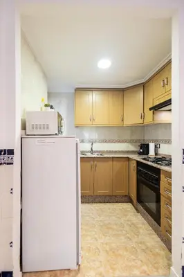 a kitchen with wooden cabinets and a white refrigerator at La casita de pescadores by Concept Flats in Valencia