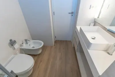 a white bathroom with a toilet and a sink at Exquisita Villa Frente al Mar in Sagunto