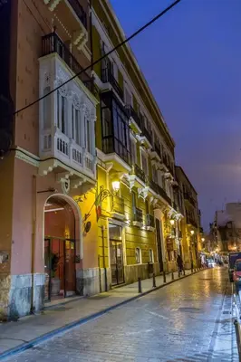 a street at night with a yellow building at Palacio de Rojas by Moontels in Valencia