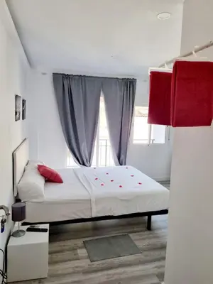 a bedroom with a bed with red pillows and a window at Apartamentos T5 Valencia in Torrent