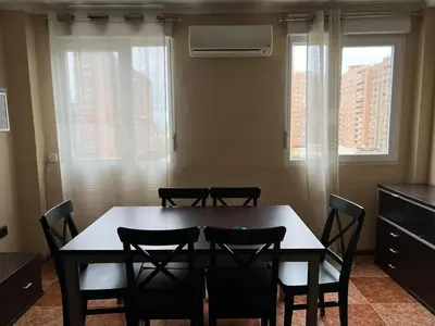 a dining room table with four chairs and two windows at Bonito y grande apartamento cerca de la playa in Valencia