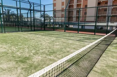 a tennis court with a net in front of a building at Florazar I frente a la playa in Cullera