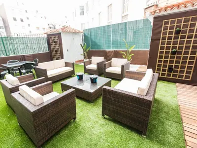 a patio with wicker chairs and tables on a rooftop at Total Valencia Terrace in Valencia