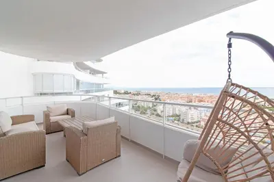 a balcony with wicker chairs and a swing at Global Vacacional, Apartamento con vistas al mar, 2 terrazas y piscina en Canet d'en Berenguer in Canet de Berenguer