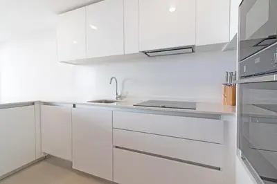 a white kitchen with white cabinets and a sink at Global Vacacional, Apartamento con vistas al mar, 2 terrazas y piscina en Canet d'en Berenguer in Canet de Berenguer