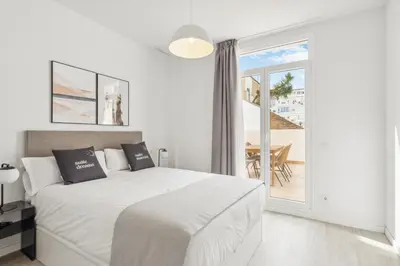 a white bedroom with a bed and a balcony at Limehome Valencia Calle de Cadiz in Valencia