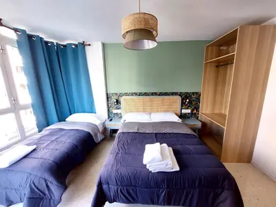 two beds in a room with blue curtains at Habitaciones Barra89 in Valencia