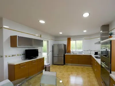 a large kitchen with wooden cabinets and stainless steel appliances at Casa Chalet Villa con piscina, jardín y aire acondicionado cerca de Valencia en La Eliana-L'Eliana in La Eliana