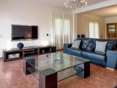 a living room with a blue couch and a tv at Casa Chalet Villa con piscina, jardín y aire acondicionado cerca de Valencia en La Eliana-L'Eliana in La Eliana