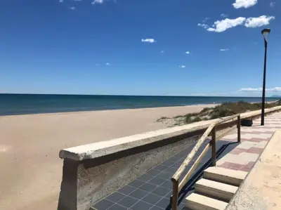 a bench on the beach next to the ocean at Casa adosada junto a la playa de El Perelló in Sueca