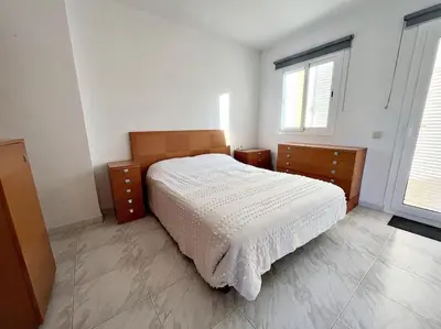a bedroom with a white bed and two windows at Casa adosada junto a la playa de El Perelló in Sueca