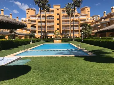 a swimming pool in front of a large building at Casa adosada junto a la playa de El Perelló in Sueca