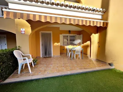 a patio with chairs and a table in a house at Casa adosada junto a la playa de El Perelló in Sueca