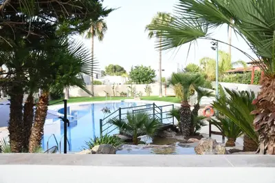 a swimming pool with palm trees and a garden at Holiday Home Valencia in Riba-Roja De Turia