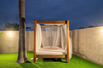 a canopy bed on the grass next to a palm tree at Holiday Home Valencia in Riba-Roja De Turia