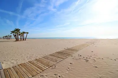 a beach with footprints in the sand and palm trees at Global Vacacional, Apartamento con piscina y terraza en Canet in Canet de Berenguer