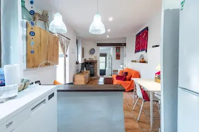 an open kitchen and living room with an orange couch at EL SECADERO in Alcudia de Veo