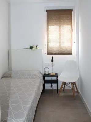 a bedroom with a bed and a chair and a window at Piso Cerca Universidades y de la Playa in Valencia