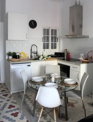 a kitchen with a table and white chairs and a counter at Piso Cerca Universidades y de la Playa in Valencia