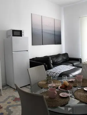 a living room with a table and a refrigerator at Piso Cerca Universidades y de la Playa in Valencia