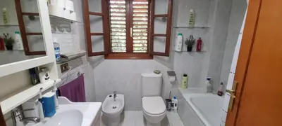 a bathroom with a toilet and two sinks and a tub at Casa en la playa in Sagunto