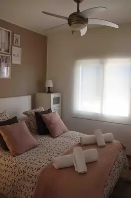 a bedroom with two beds with pillows and a fan at Precioso apartamento con vistas al mar. Piscina. in Valencia