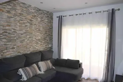 a living room with a couch and a brick wall at Precioso apartamento con vistas al mar. Piscina. in Valencia