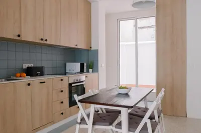 a kitchen with a wooden table and white chairs at La Alfarería in Valencia