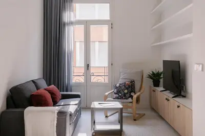 a living room with a couch and a chair and a tv at La Alfarería in Valencia