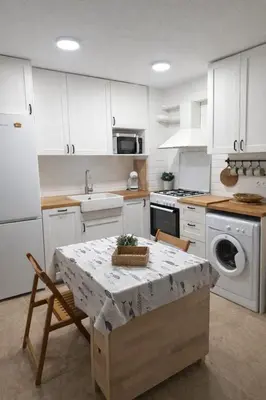 a kitchen with white cabinets and a table with a basket on it at Bonito apartamento con vistas al mar in Playa Pobla de Farnals