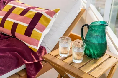 a table with a green vase and glasses on it at Gran Canet 2BR! Walk to Beach, Sea View, Sauna & Gym in Canet de Berenguer
