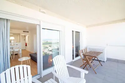 a living room with a balcony with a table and chairs at Global Vacacional, Moderno apartamento con piscina en la playa de Canet in Canet de Berenguer