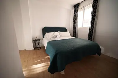 a bedroom with a bed with a green blanket and a window at Casa Ross en Ruzafa in Valencia