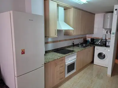 a kitchen with wooden cabinets and a white refrigerator at Apartamento en el Grau de Moncofa entre 2 y 3 linea de playa in Moncófar