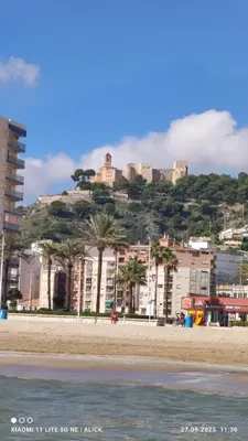 a beach with buildings and palm trees and a hill at Apartament CullerA in Cullera
