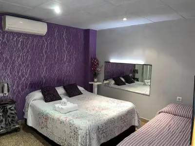 a purple bedroom with two beds and a mirror at Hostal Happystay in Valencia