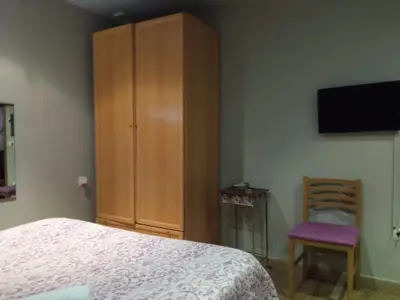 a bedroom with a bed and a cabinet and a chair at Hostal Happystay in Valencia