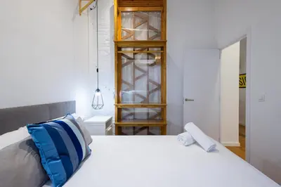 a bedroom with a white bed and a wooden shelf at FLORIT FLATS - The Vella Apartment in Valencia