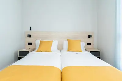 a bedroom with two beds with yellow pillows at Dorm4You Arena 2 in Valencia