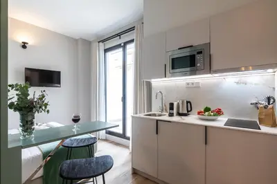 a kitchen with white cabinets and a table with two stools at Moontels Mercado de Ruzafa in Valencia