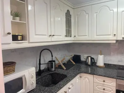 a kitchen with white cabinets and a sink at Apartamento en complejo residencial con piscina y garaje a 100m del mar in Las Canteras
