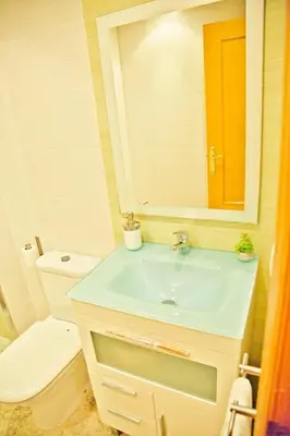 a bathroom with a sink and a toilet and a mirror at Apartamento Playa Xilxes in Xilxes
