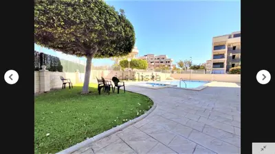 a patio with chairs and a tree next to a pool at CANET PLAYA MAGNIFICO APTO FAMILIAR con PISCINA y GARAJE in Canet de Berenguer