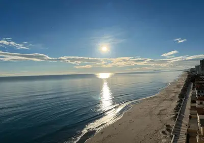 a beach with the sun reflecting in the water at Apartamento Rey I in Valencia