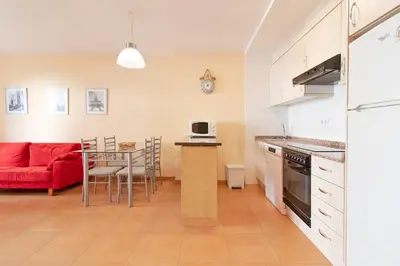 a kitchen and living room with a red couch and a table at Global Vacacional, Práctico apartamento en la playa de Canet in Canet de Berenguer