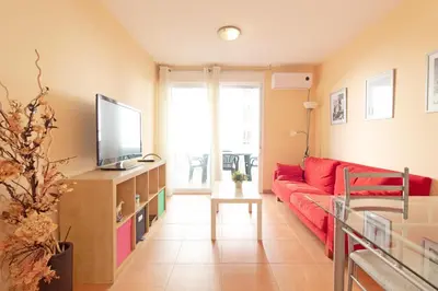 a living room with a red couch and a tv at Global Vacacional, Práctico apartamento en la playa de Canet in Canet de Berenguer